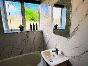 a bathroom with a sink and a tub and a mirror at Spacious 3 Bed House in Northampton - Sleeps 6 - Driveway Parking - Fast WiFi in Kingsthorpe +22 photos