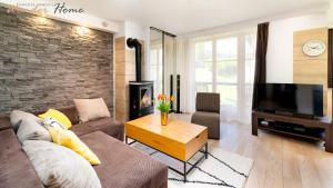 a living room with a couch and a tv at Wonder Home - Domki górskie z kominkami na kameralnym osiedlu - plac zabaw na terenie kompleksu in Karpacz