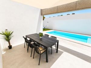 a black dining table and chairs next to a swimming pool at Villa Drago in Antigua