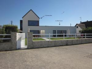 une clôture blanche devant une maison blanche dans l'établissement Gites "Bord de Mer" PMR ou "Arromanches" 2 chambres en FRONT DE MER à Asnelles , 3km d'Arromanches, 10km de Bayeux, à Saint-Côme-de-Fresné