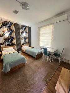 a bedroom with two beds and a desk and a table at Sayak hotel & hostel in Karakol