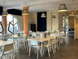 a restaurant with wooden tables and white chairs at Grantek Üdülőház in Balatonlelle