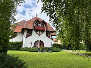 a house with two chairs on a lawn at Grantek Üdülőház in Balatonlelle