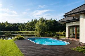 a swimming pool on a wooden deck next to a pond at Argentum Private Residence Basen Sauna Jacuzzi in Koszelówka