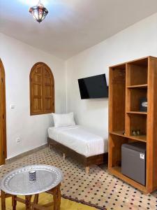 a bedroom with a bed and a table and a tv at Riad Fes Colors & SPA - Family Lodging in Fez