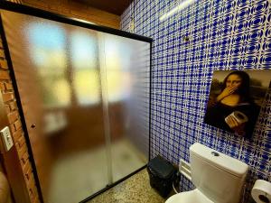 a bathroom with a toilet and a picture of a woman at Suíte com Ar condicionado no Centro de Botucatu in Botucatu