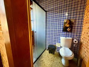 a bathroom with a toilet and a tile wall at Suíte com Ar condicionado no Centro de Botucatu in Botucatu
