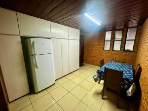 a kitchen with a table and a refrigerator in it at Suíte com Ar condicionado no Centro de Botucatu in Botucatu