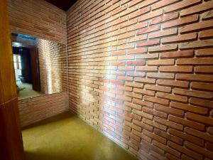 an empty room with a brick wall and a mirror at Suíte com Ar condicionado no Centro de Botucatu in Botucatu +19 photos