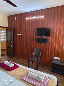 a room with a bed and a chair and a television at Hotel Tamilnadu-Unit 2 in Rāmeswaram