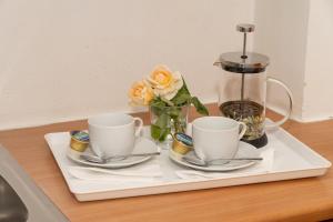 two cups and saucers on a tray with flowers at Posidonia Pension in Amarynthos