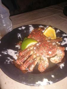 a crab on a plate with a lime and a lemon slice at Grotte de pêcheurs Tigri in Aglou