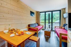a living room with a table and a couch at Résidence Vacancéole - Privilège in Germ