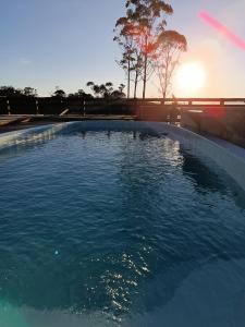 a large swimming pool with the sunset in the background at Chalés Refúgio nas montanhas in Guaratuba