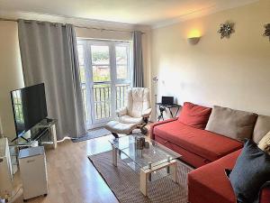 a living room with a red couch and a tv at Hunters Wharf River View by Select SA in Reading