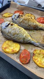 a group of fish on a baking pan with tomatoes at Grotte de pêcheurs Tigri in Aglou