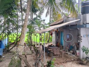 a table and chairs outside of a house with palm trees at Lakecampers for foreign travellers in Alleppey