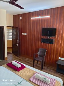 a bedroom with a bed and a chair and a television at Hotel Tamilnadu-Unit 2 in Rāmeswaram
