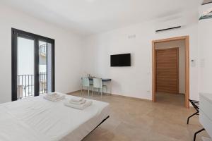 a white room with a bed and a television at ByAma Holiday House in Menfi