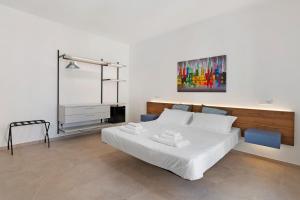 a bedroom with a white bed and a painting on the wall at ByAma Holiday House in Menfi