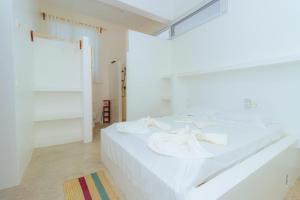 a white bedroom with a large bed with white sheets at Lilo House in Watamu
