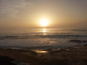 a sunset over the ocean with the sun in the sky at Grotte de pêcheurs Tigri in Aglou