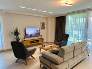 a living room with a couch and chairs and a television at Prime Bodrum Villas in Bodrum City