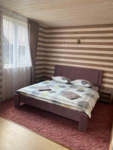 a bed in a bedroom with a striped wall at Шепіт Лісу in Yaremche
