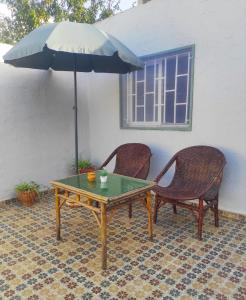 a table and two chairs and an umbrella at Petit villa centre harhoura Près de la plage in Temara