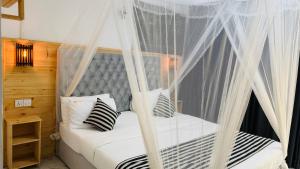 a bedroom with a canopy bed with black and white pillows at Mount Breeze Ella in Ella