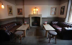 a waiting room with leather couches and a fireplace at The Horse & Farrier in Otley