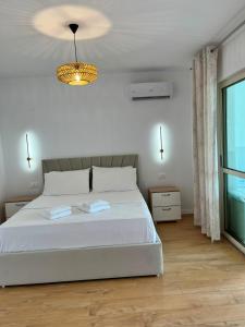 a white bedroom with a bed and a chandelier at Lake Breeze in Gjokaj