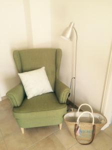 a green chair with a pillow and a lamp and a basket at Haus Charlotte in Fehmarn