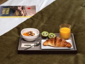 a tray with a plate of food and a bowl of fruit and a glass at Lazare Nomade in Paris