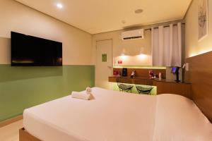 a bedroom with a large white bed and a kitchen at Spa Motel - Radial Leste in São Paulo +27 photos