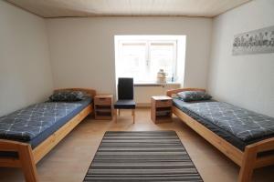 two beds in a room with a desk and a window at IBS Wohnen in Windischeschenbach