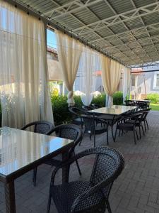 a group of tables and chairs under a patio with curtains at Saty Guest House in Saty