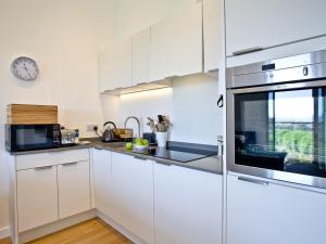 a kitchen with white cabinets and a clock on the wall at Una Aurum 56 in St Ives