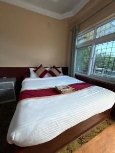 a bedroom with a large white bed with a window at Pahuna Ghar Homestay in Tānsen