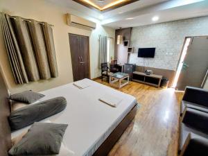a bedroom with a white bed and a television at Hotel Alka in Varanasi