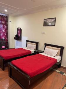 two beds with red sheets in a room at Milan Hotel in Zahirābād