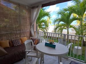 a balcony with a table and a couch and palm trees at Just in paradise in Baie Nettle