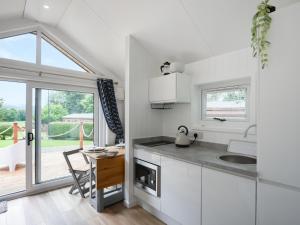 a kitchen with white cabinets and a table and a dining room at Mini Lodge - Uk47682 in Montgomery