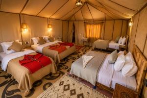 a bedroom with three beds in a tent at Rosara Luxury Camp in Merzouga