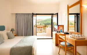 a hotel room with a bed and a desk and a window at Mitsis Ramira in Kos +56 photos