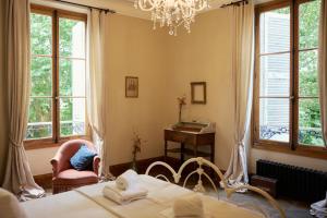 a bedroom with a bed and a chair and windows at Chateau Gioux in Saint-Pierre-Bellevue