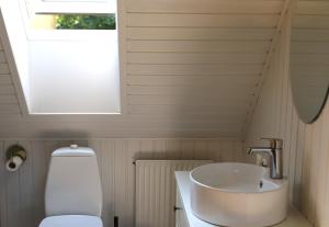 a bathroom with a sink and a toilet and a window at Lønstrup Strandhotel in Lønstrup +29 photos