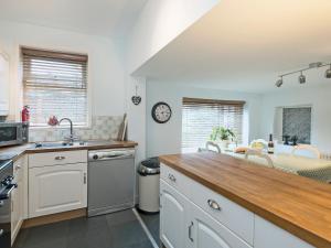 a kitchen with white cabinets and a wooden counter top at Horseshoe House - Ukc2743 in Watton +10 photos