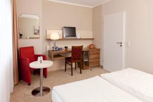 a hotel room with a bed and a desk with a computer at Akzent Hotel Bavaria Oldenburg in Oldenburg +75 photos