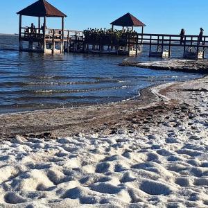 a sandy beach with a pier in the water at Los Aromos Carhue in Carhué